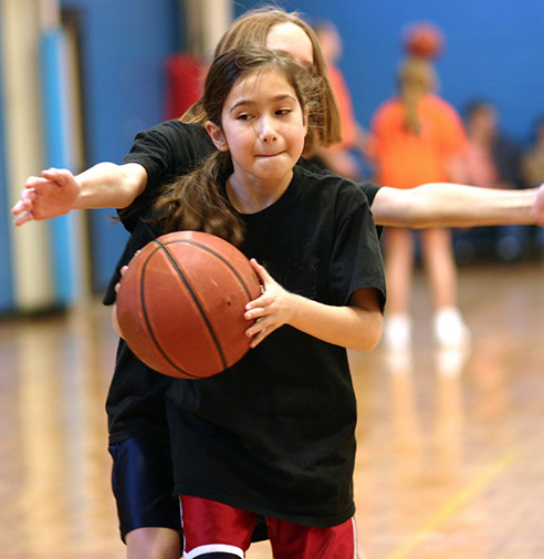 Two young females playing indoor basketball