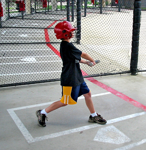 Young male swinging a bat in the batting cages at SportOhio