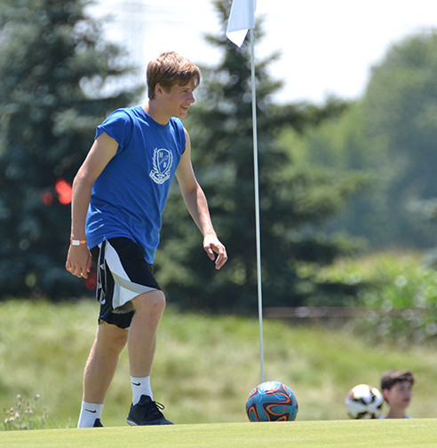 Male teen FootGolf player about to kick ball on golf course