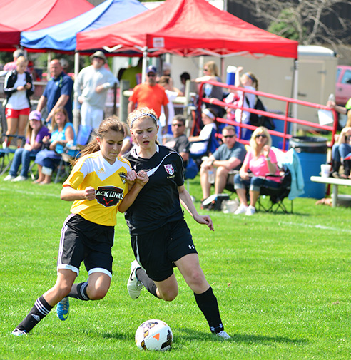 Two female teens battling for a soccer ball during an outdoor tournament at Soccer First at SportsOhio
