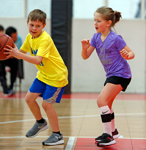 Young male & female playing indoor basketball
