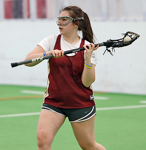 Female teen lacrosse player passing ball